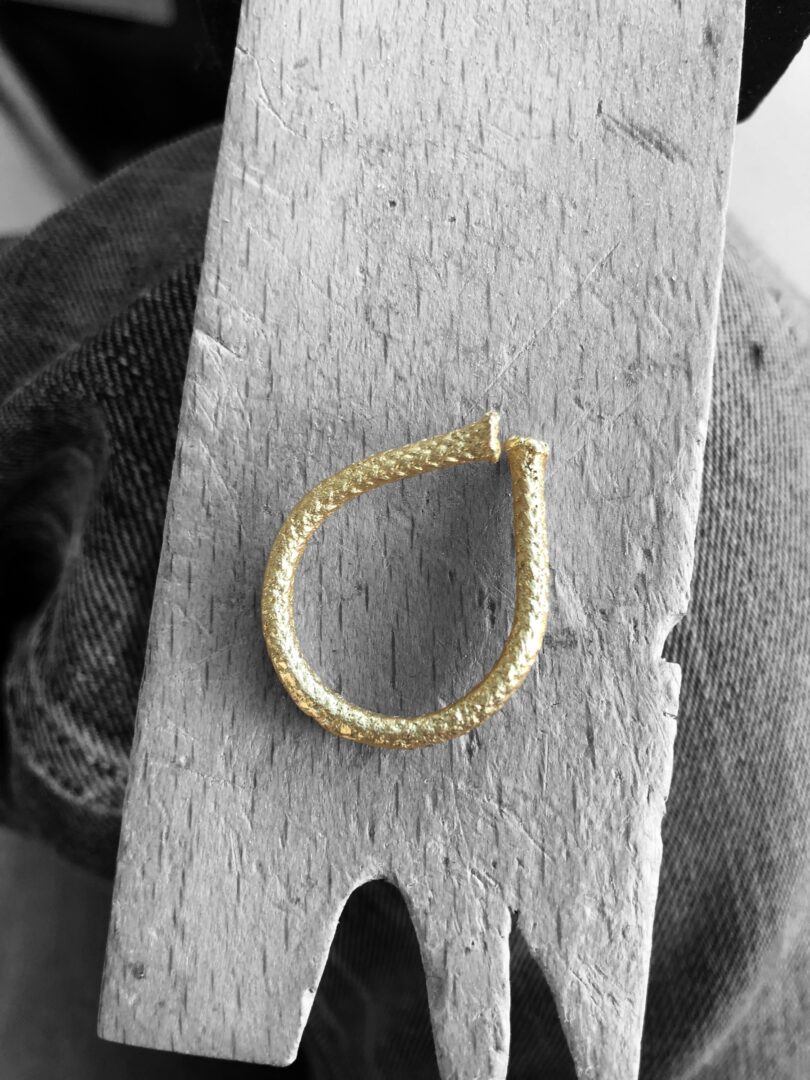 A handcrafted Golden open rope ring, with its 24k gold-plated texture, rests elegantly on a wooden surface, highlighting its meticulous design.