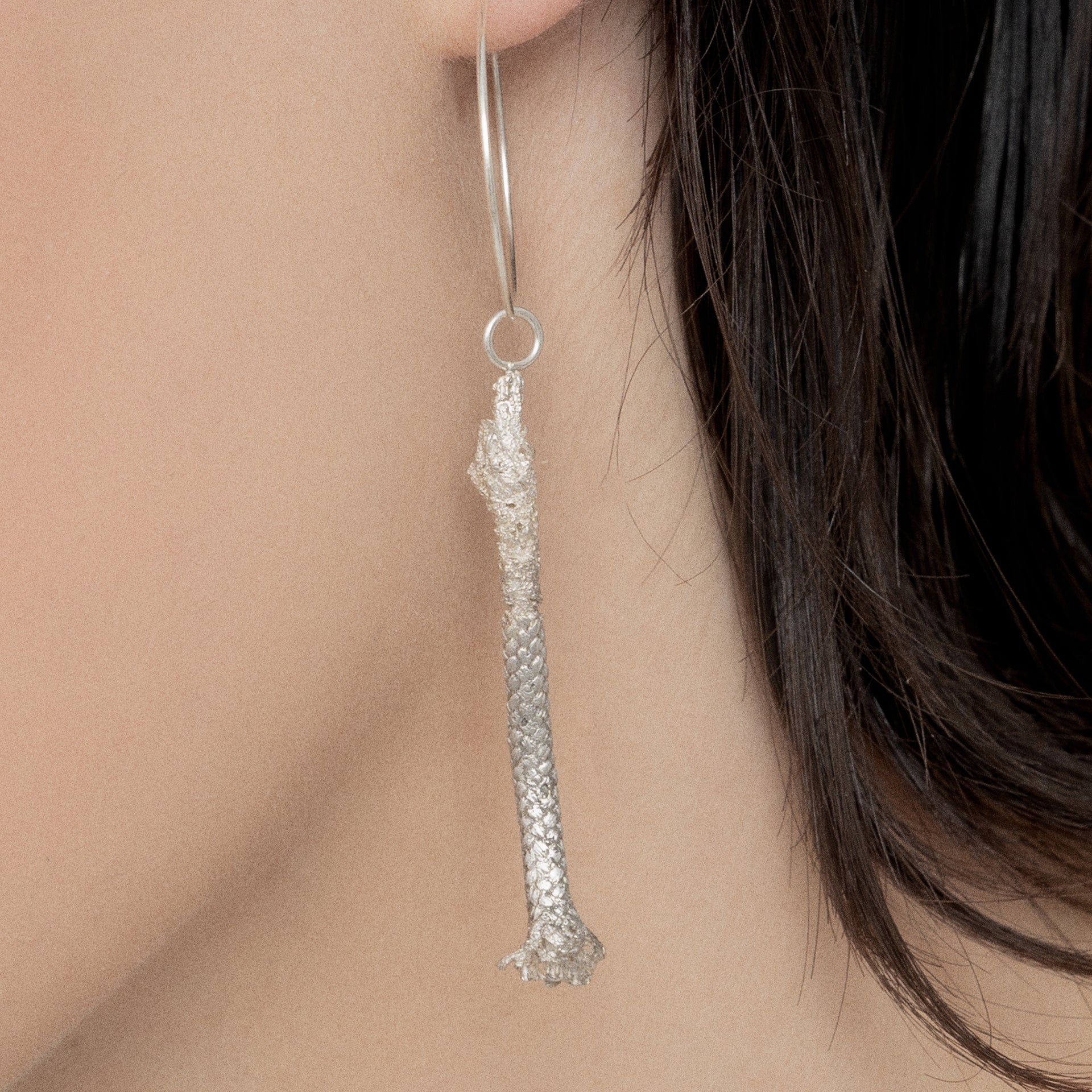 Close-up of a person's ear adorned with an artisan-made, Thin Hoop Nautical Earring featuring a Sterling Silver Rope.