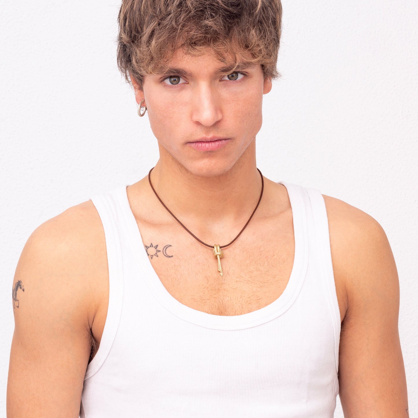 Person wearing a white tank top and the Ballestrinque Small Nautical Knot Pendant in Sterling Silver, looking directly at the camera.