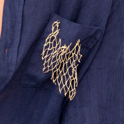 Close-up of a handmade, one-of-a-kind ocean-inspired fishing net brooch with intricate gold embroidery, showcasing unique pieces reminiscent of fine artworks.