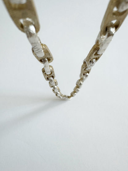 Close-up of a nautical silver chain with intricate design on a light gray background