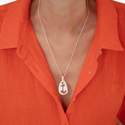 A person wearing a bright orange button-up shirt with an Anchor Sketch Pendant Inspired by Bernard Moitessier’s Spirit in sterling silver.