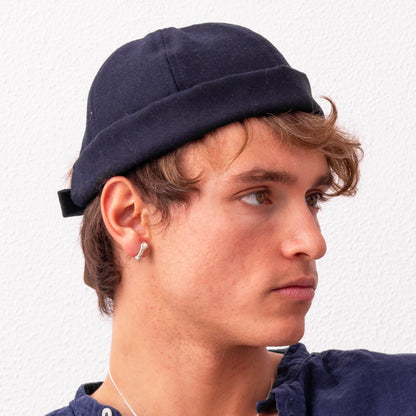 A person with light brown hair wearing a dark rolled-up beanie and a Sterling Silver Rope S Earring: Handmade Nautical Jewel looks to the side against a white background.