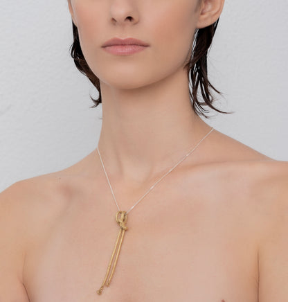 A person with short, wet hair wears a necklace featuring an Artisanal Made Ballestrinque Nautical Knot Pendant on a thin chain against a plain background.