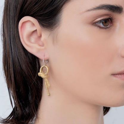 Close-up of a person wearing a Nautical golden knot pendant - Ballestrinque S, against a plain background.