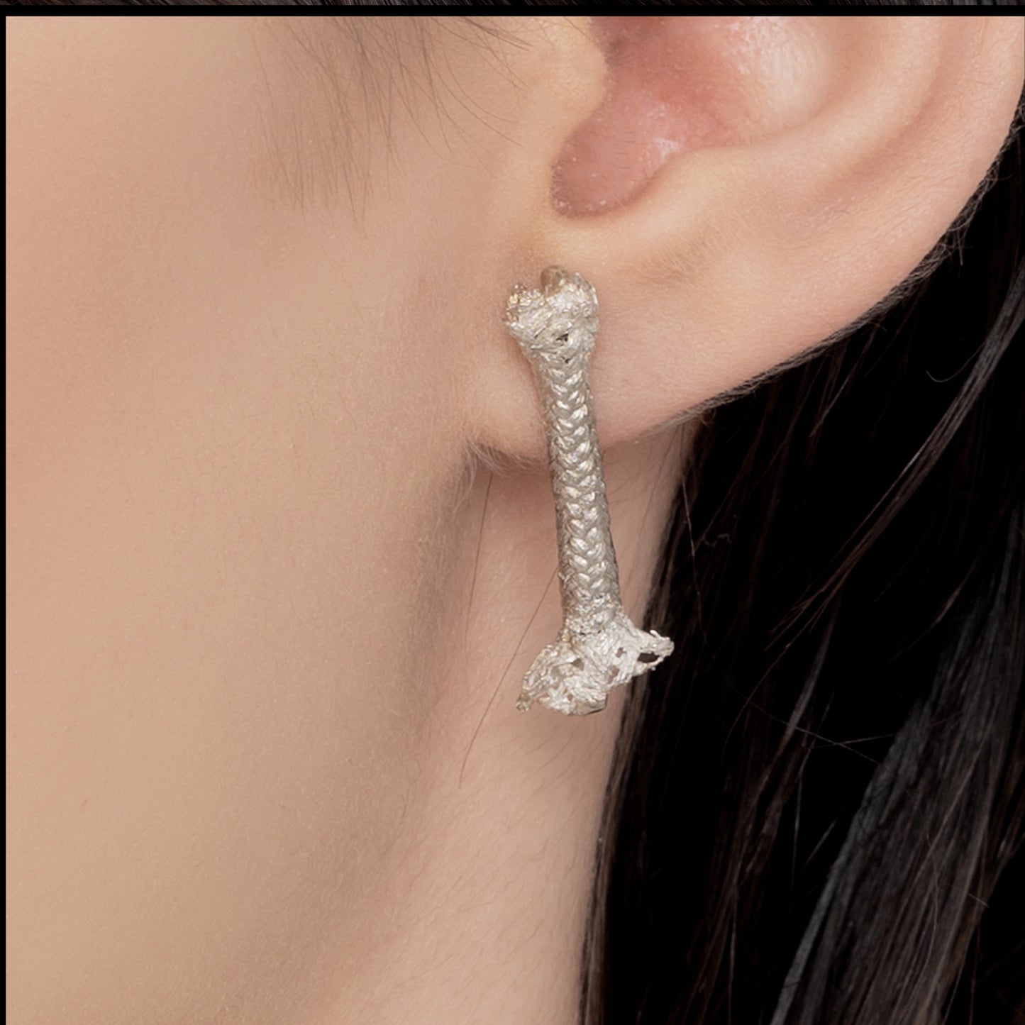 Close-up of a person's ear wearing an Angela Lago earring in the shape of a rope, crafted from 100% Sterling silver.