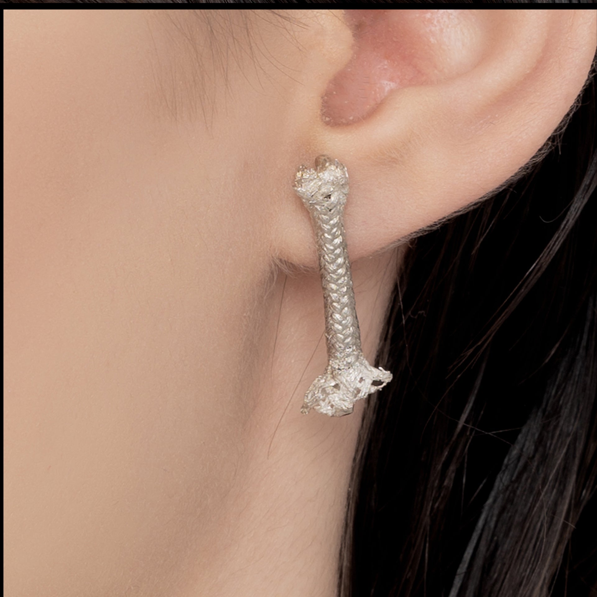 Close-up of a person's ear wearing an Angela Lago earring in the shape of a rope, crafted from 100% Sterling silver.